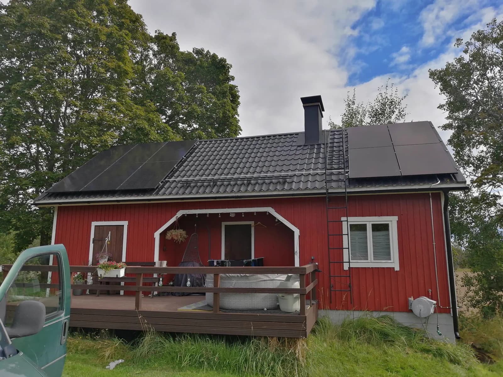 Aurinkopaneelit punaisen puutalon katolla